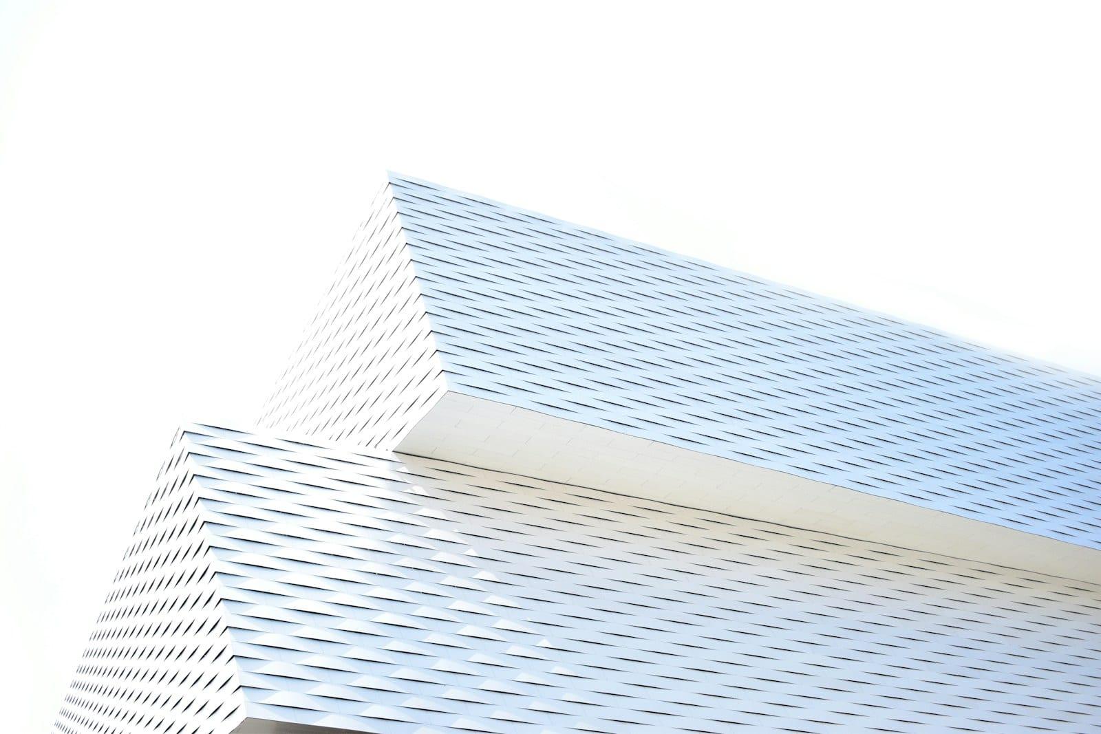 White louvred concrete facade seen from below against a pale sky